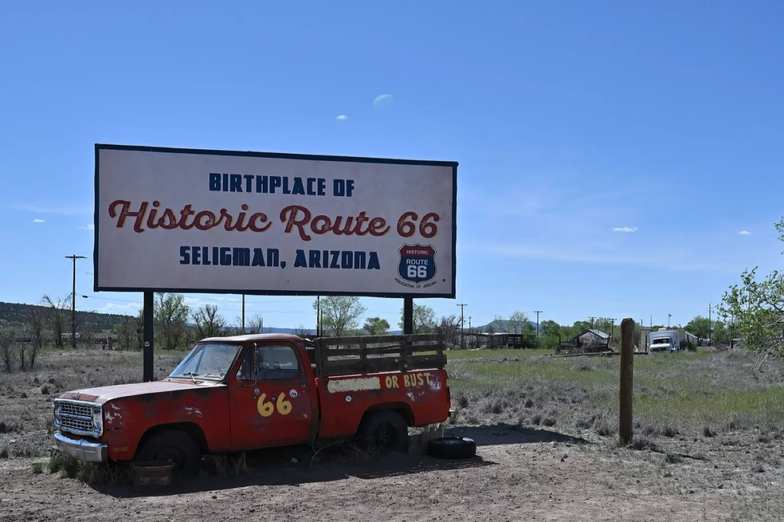 A sign reading Birthplace of Historic Route 66, Seligman, Arizona, above a red pickup truck