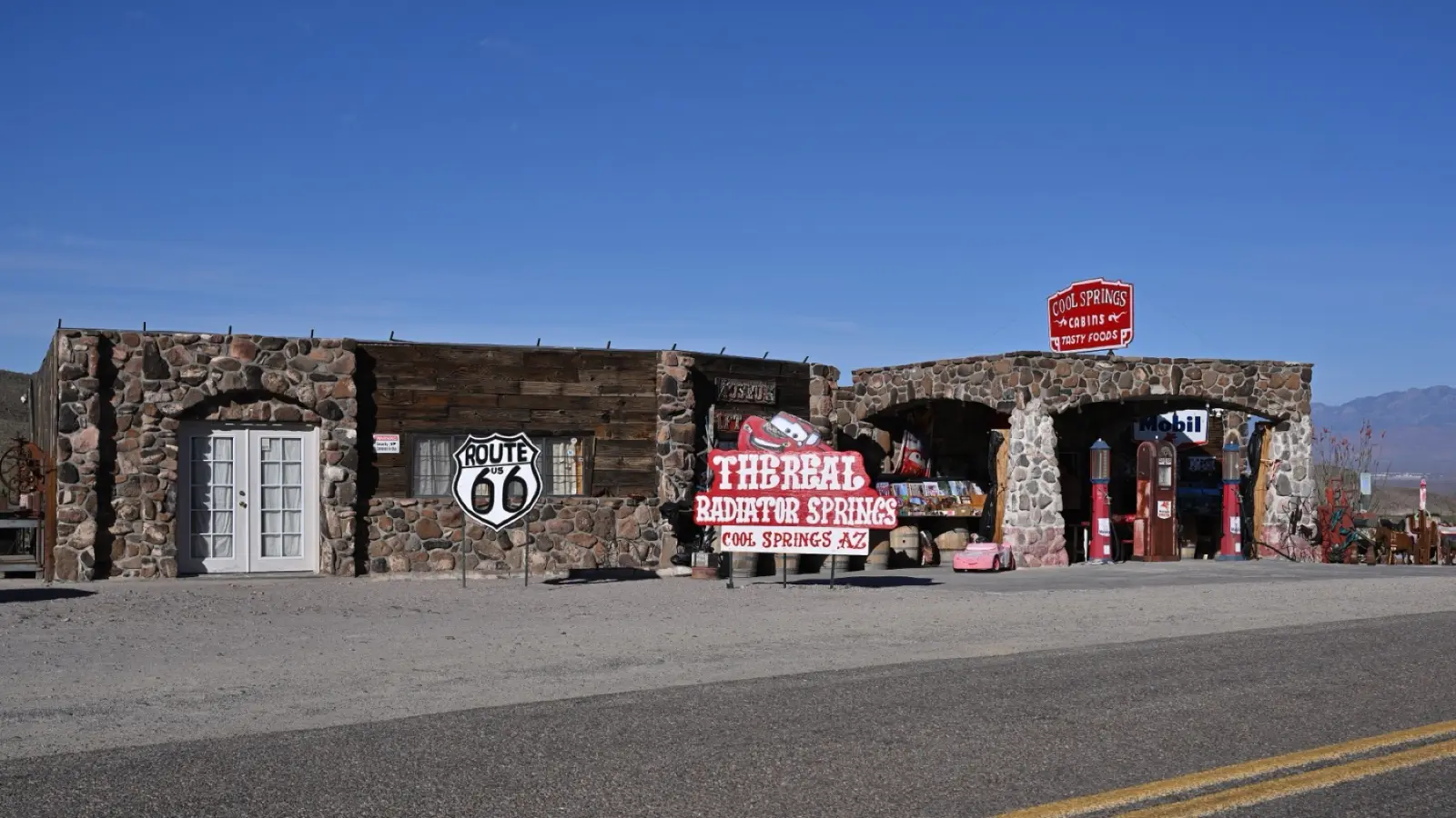 Stone buildings of Cool Springs Station with a Route 66 shield sign and old gas pumps on the Oatman Road, Arizona