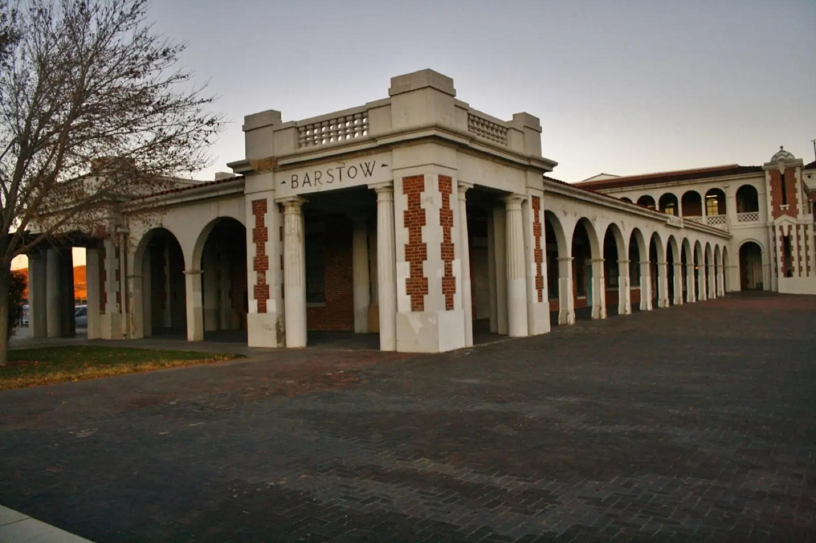 The arched brick and white colonnade of the Barstow Harvey House, Casa del Desierto, with BARSTOW carved above the entrance