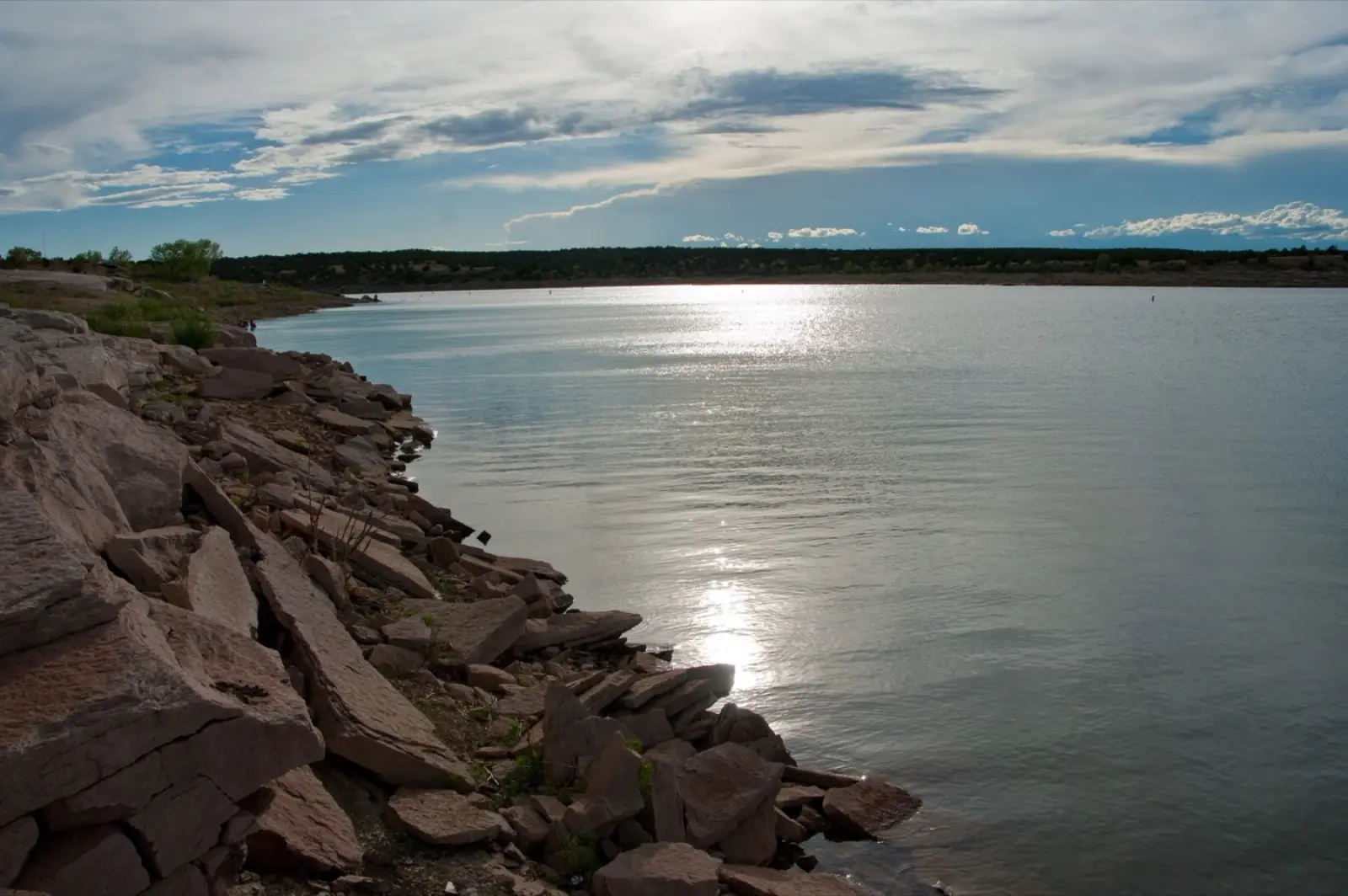 Santa Rosa Lake in New Mexico at evening, with red rock along the shore and sunlight on the water