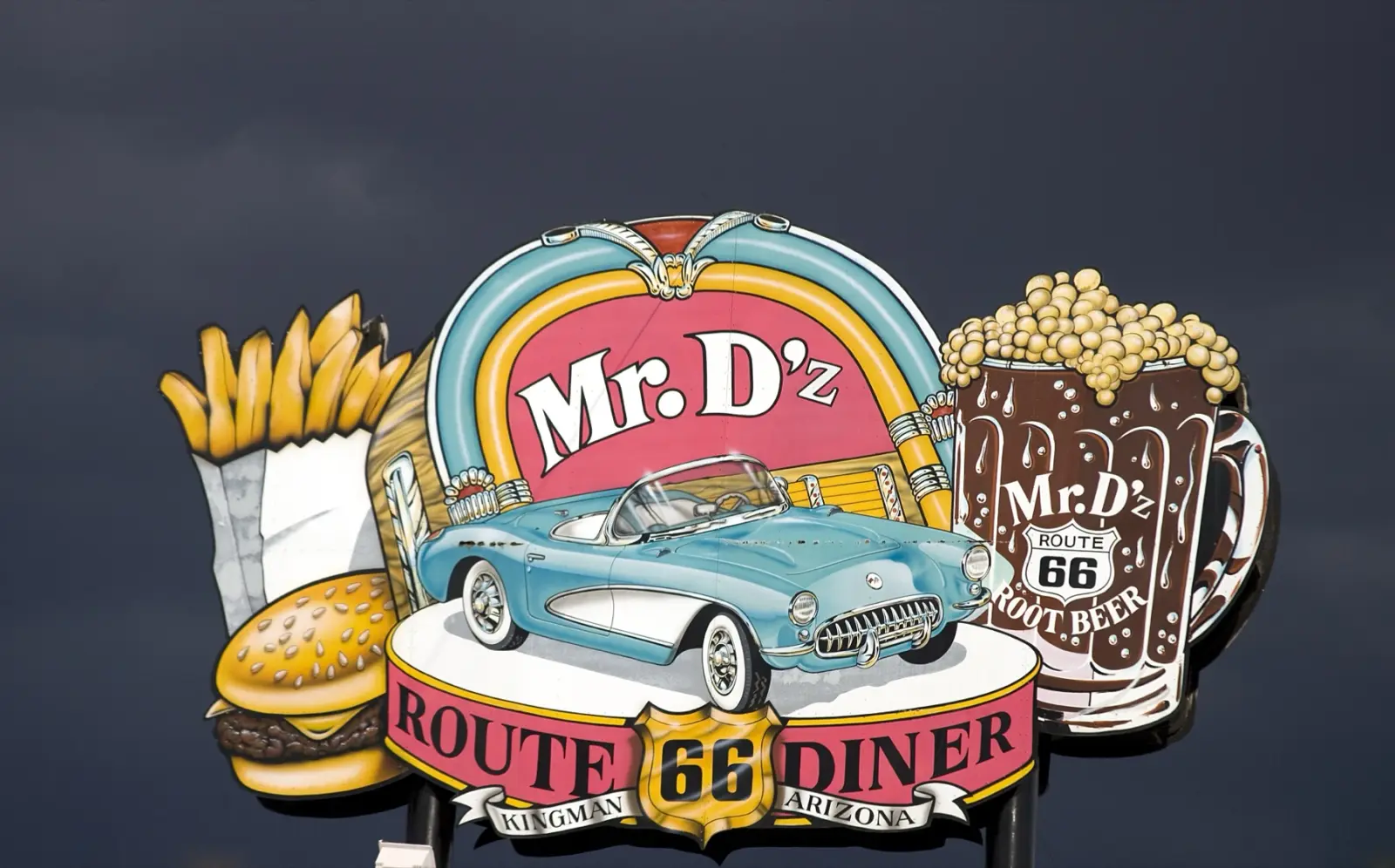 The painted sign of Mr. D'z Route 66 Diner in Kingman, Arizona: a jukebox, a turquoise Corvette, a burger, fries and a mug of root beer