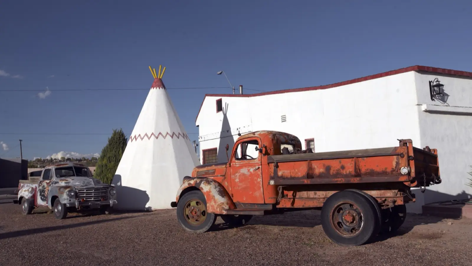 A white concrete teepee and a rusted orange vintage truck at the Wigwam Motel in Holbrook, Arizona