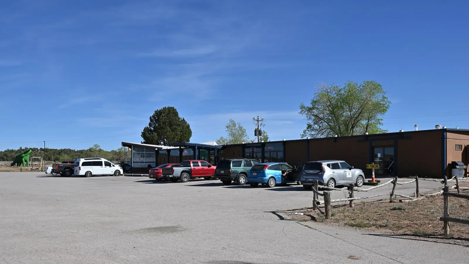 The Grand Canyon Caverns store and parking lot on Route 66 near Peach Springs, Arizona, with a green dinosaur statue on the left