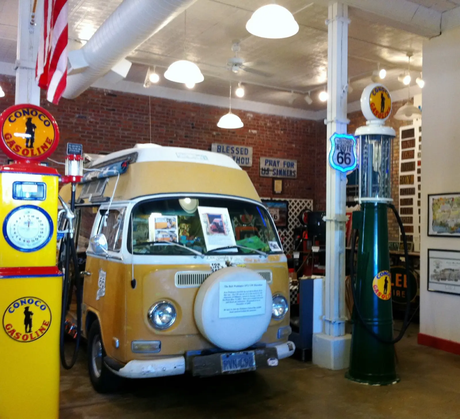 Bob Waldmire's yellow and white Volkswagen van parked inside the Route 66 museum in Pontiac, Illinois, between vintage Conoco and Shell gas pumps