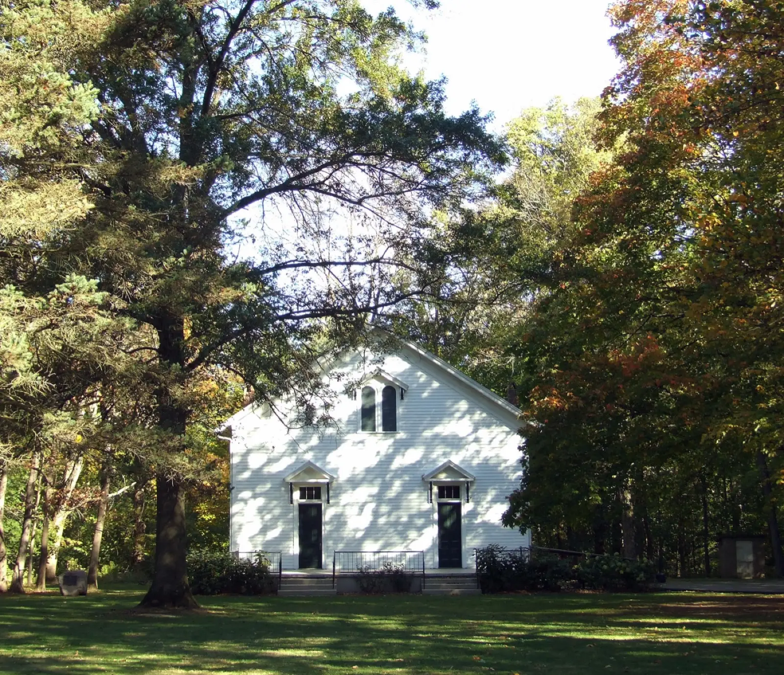 White wooden Funks Grove chapel framed by trees beginning to turn orange in October