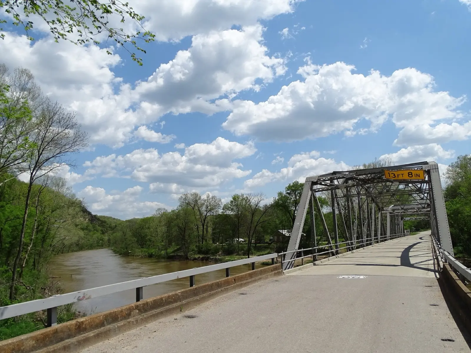 Narrow concrete deck of the Devils Elbow steel truss bridge on old Route 66 over the Big Piney River in Missouri, with spring trees along the water