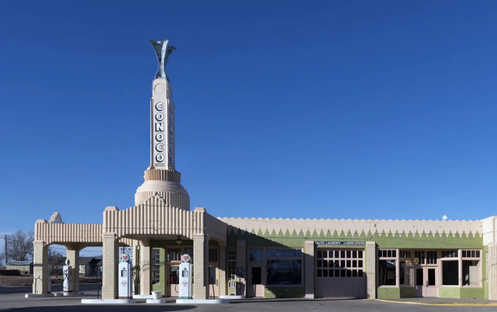 Art Deco Tower Conoco station and U-Drop Inn in Shamrock, Texas, with its tall tower and green and cream facade under a clear blue sky