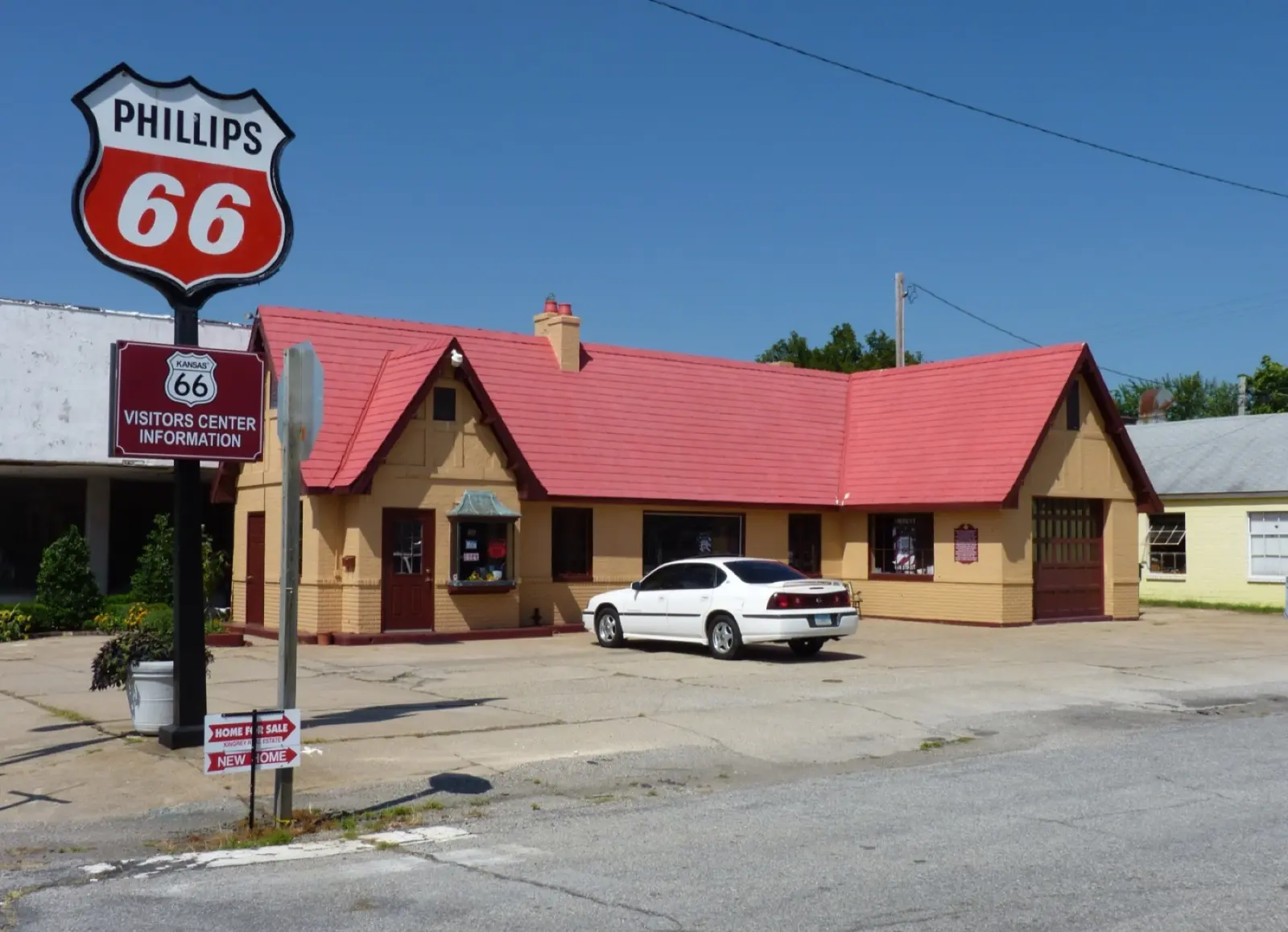 Tan cottage-style former Phillips 66 station with a red roof and a Phillips 66 shield sign, now the Kansas Route 66 Visitor Center in Baxter Springs