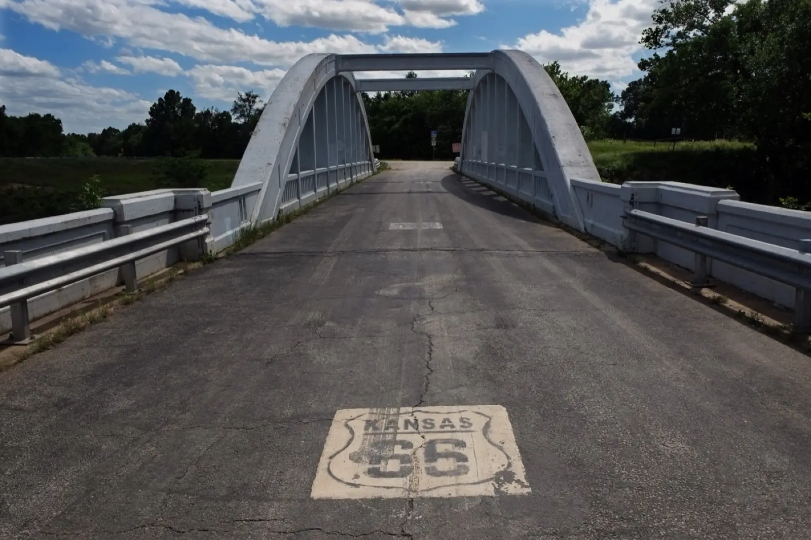 The white concrete Rainbow Bridge over Brush Creek near Riverton, Kansas, with a Kansas Route 66 shield painted on the road