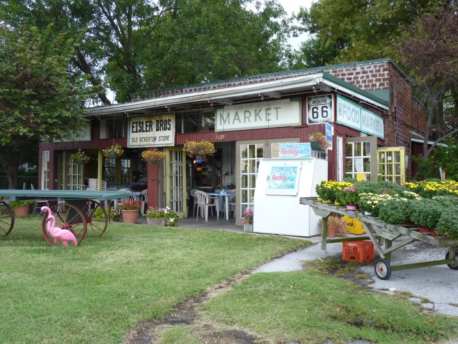 The Old Riverton Store in Riverton, Kansas, with an Eisler Bros sign, a Route 66 shield, flowers and a pink flamingo out front