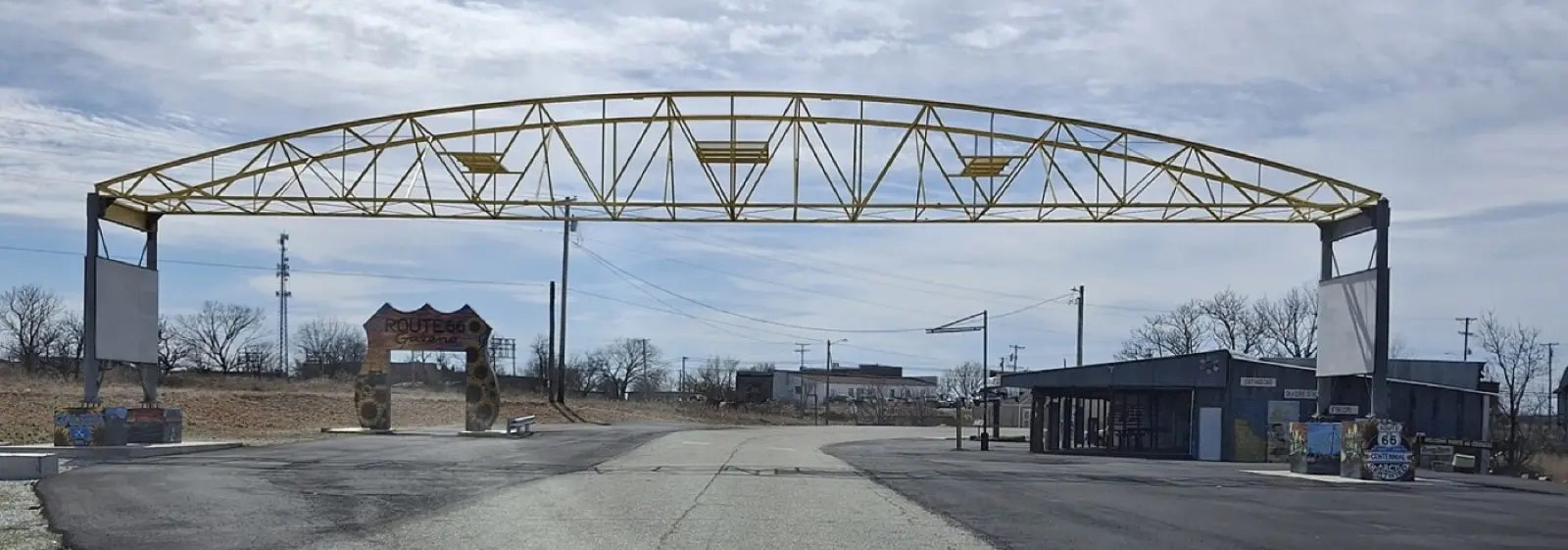 Long yellow steel truss arch spanning Route 66 in Galena, Kansas, with a Route 66 Galena sign and old buildings under a winter sky