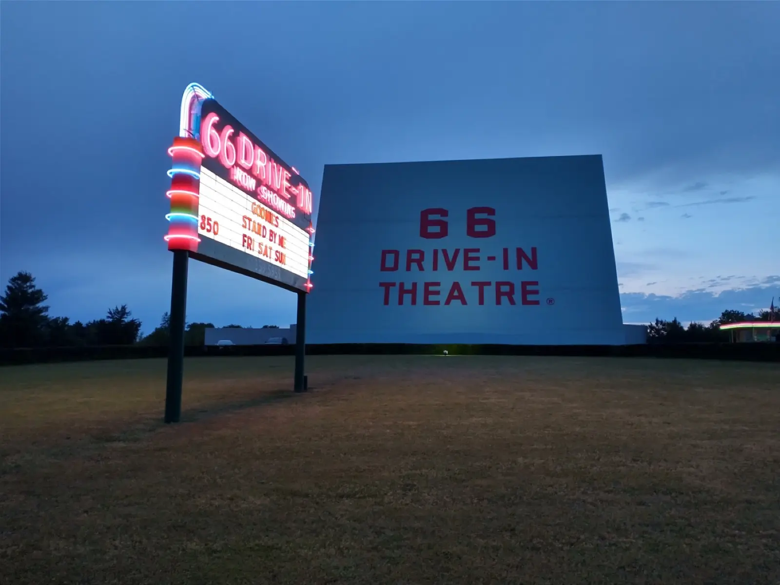 The lit neon marquee and the white screen of the 66 Drive-In Theatre in Carthage, Missouri, at twilight