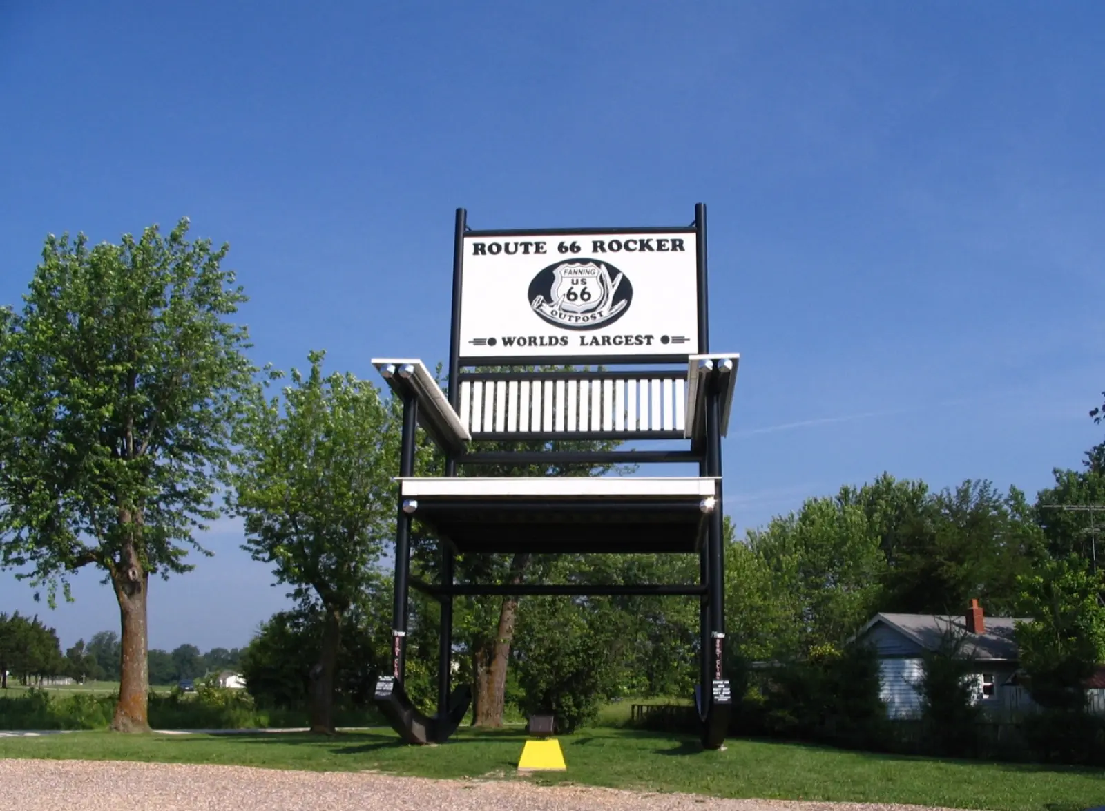 The giant black steel rocking chair at Fanning, Missouri, with a Route 66 Rocker World's Largest sign on top, under a blue sky