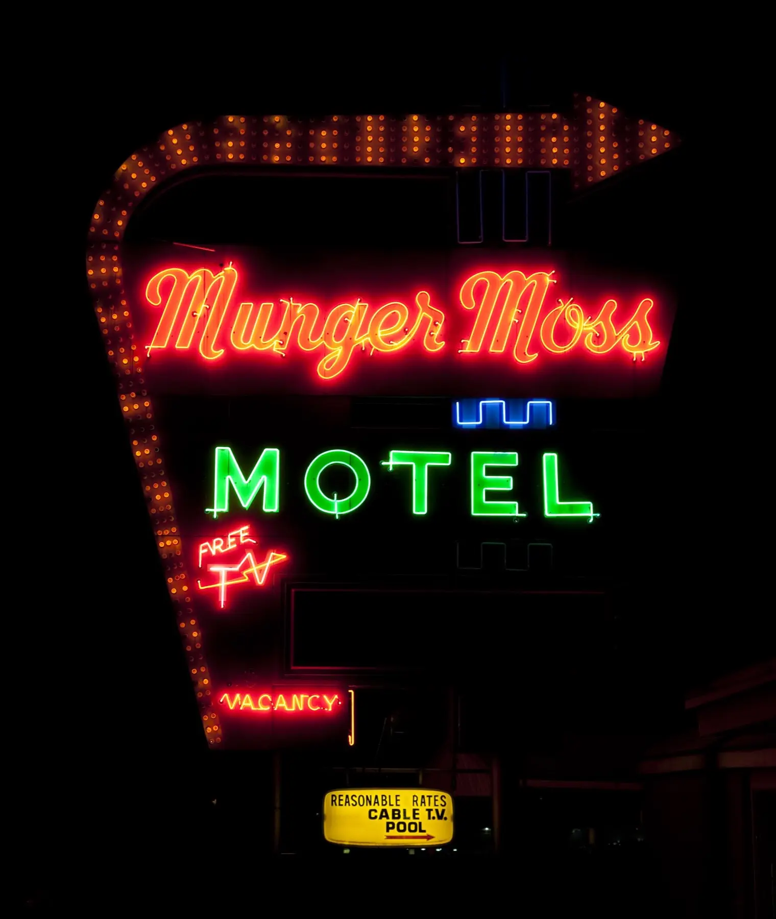 The tall Munger Moss Motel neon sign with its arrow and Route 66 lettering against a blue sky in Lebanon, Missouri