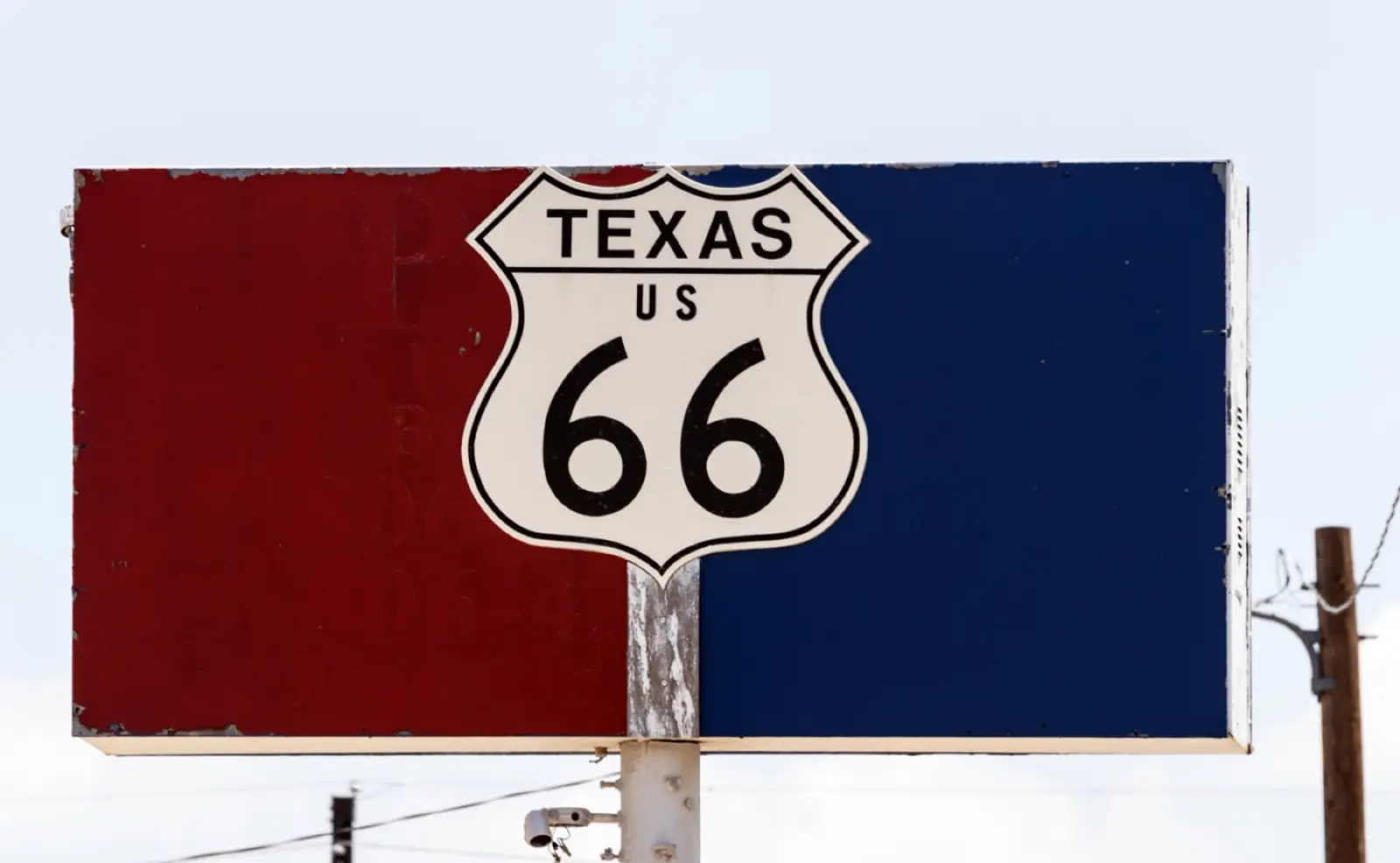 Texas US 66 highway shield mounted on a faded red and blue sign in Amarillo, Texas