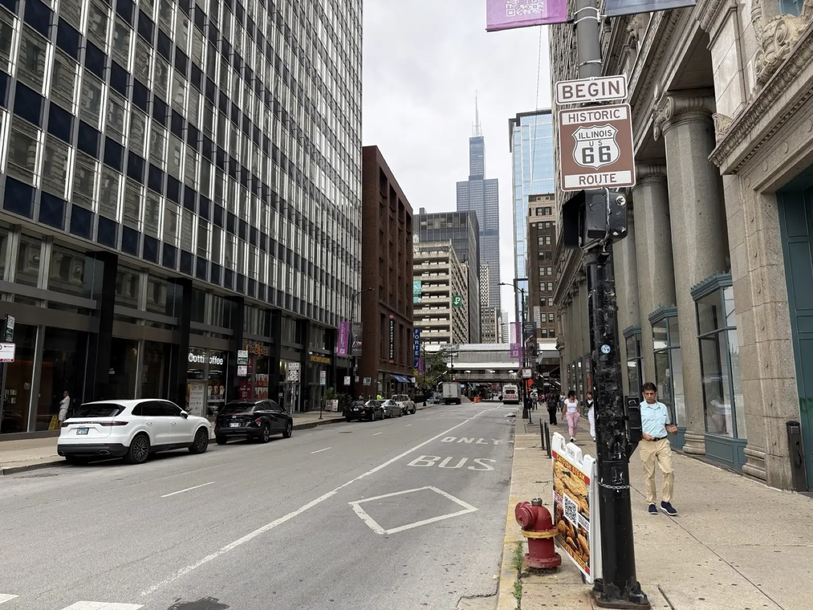 Begin Historic Route 66 sign on a pole on the north side of Adams Street in Chicago, with the street running west toward the Willis Tower