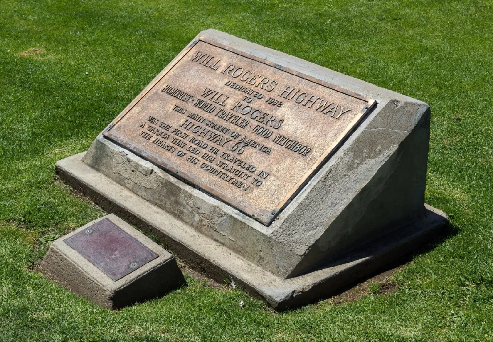 Bronze Will Rogers Highway plaque dedicated in 1952, set in a concrete block on the grass of Palisades Park in Santa Monica